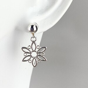 May include: Silver snowflake dangle earrings with a round silver bead at the top.