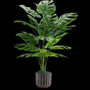 May include: An artificial Monstera plant with large, green, split leaves. The plant is in a black and gold geometric patterned pot. The leaves have a distinctive, perforated appearance. The pot is set against a black background. The plant is a decorative item.