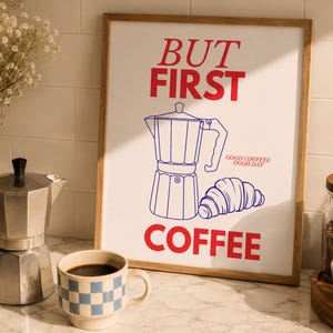 Könnte beinhalten: Ein gerahmter Druck mit den roten Worten "BUT FIRST COFFEE" und einer Kaffeemaschinenillustration. Eine silberne Espressokanne, eine blau-weiß karierte Tasse mit Kaffee und ein Glas mit Kaffeebohnen sind ebenfalls zu sehen.
