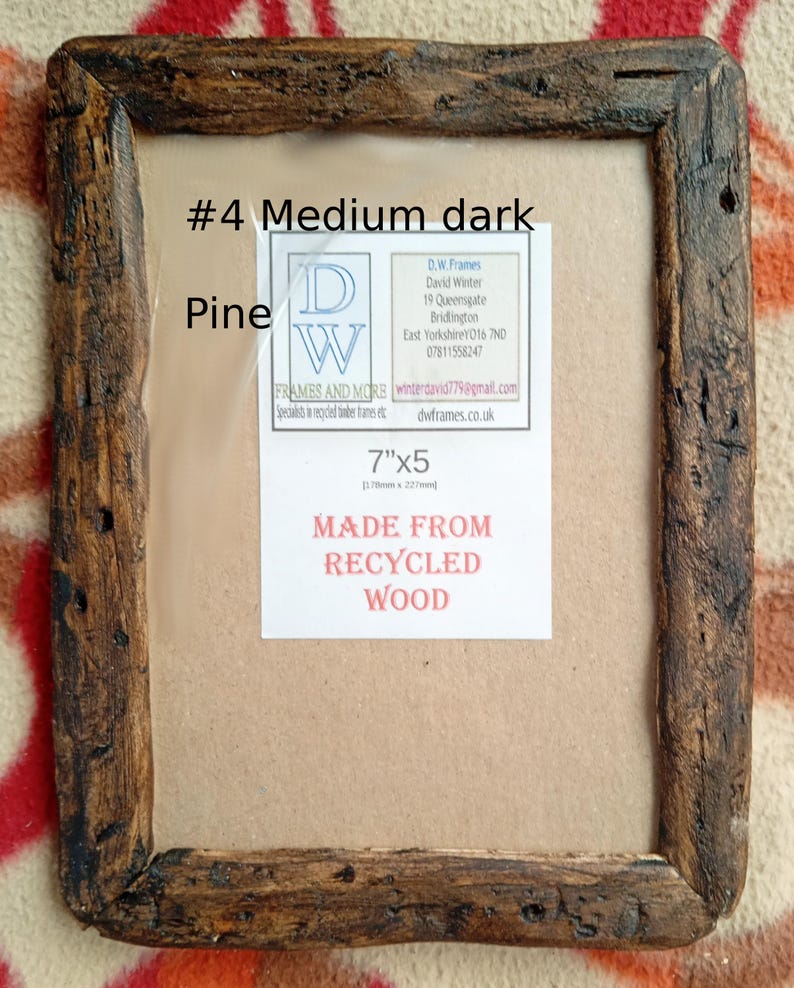 May include: A rectangular picture frame crafted from dark, weathered recycled pine wood. The frame features a rustic, textured surface and contains a white insert with the text #4 Medium dark Pine, 7"x5, and MADE FROM RECYCLED WOOD.