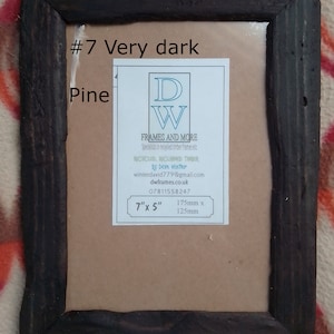 May include: A rectangular picture frame made of very dark pine wood with a rustic texture. A white label is centered inside, reading #7 Very dark Pine, DW FRAMES AND MORE, Recycled, Reclaimed Timber by Dave Winter, and 7" x 5" (175mm x 125mm).