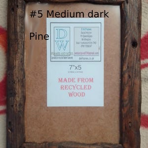May include: A rectangular picture frame made from dark brown recycled pine wood with a rustic, weathered texture. A white label in the center displays the text #5 Medium dark, Pine, 7"x5, and MADE FROM RECYCLED WOOD, along with contact details.