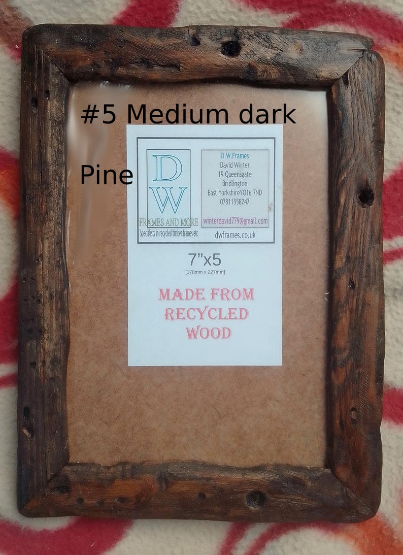 May include: A rectangular picture frame made from dark brown recycled pine wood with a rustic, weathered texture. A white label in the center displays the text #5 Medium dark, Pine, 7"x5, and MADE FROM RECYCLED WOOD, along with contact details.