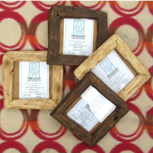 May include: Four square picture frames made of reclaimed wood in varying shades of dark and light brown. Each frame contains a white insert with the text DW FRAMES AND MORE, 4"x4", and 150mm x 150mm. The frames have a rustic, textured finish.