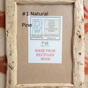 May include: A rectangular picture frame made from natural pine wood with a rough, textured finish. A label inside reads #1 Natural Pine, 7"x5", and MADE FROM RECYCLED WOOD, along with contact details for D.W. Frames and More in Bridlington.