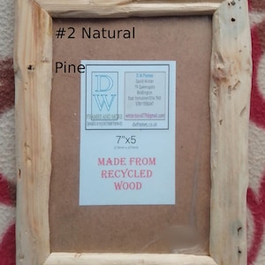 May include: A rectangular natural pine wood picture frame with a rough, unfinished texture. The frame contains a label with the text #2 Natural Pine, 7"x5", and MADE FROM RECYCLED WOOD, along with contact details for D.W. Frames and More.