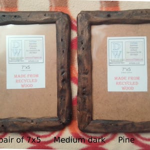 May include: A pair of rectangular picture frames crafted from dark brown recycled wood with a rough, natural texture. Each frame features a white insert label with the text 7"x5" and MADE FROM RECYCLED WOOD. The frames have a rustic appearance.