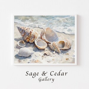 Könnte beinhalten: Ein Aquarellgemälde mit verschiedenen Muscheln, die an einem Sandstrand liegen, während sanfte Meereswellen über den Sand spülen. Das Kunstwerk zeigt eine große Spiralschale, mehrere geöffnete Muscheln und kleinere Fragmente. Text: Sage & Cedar Gallery.