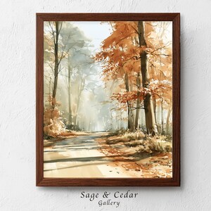 Könnte beinhalten: Ein gerahmtes Aquarellbild, das einen Waldweg im Herbst darstellt. Die Szene zeigt hohe Bäume mit orangefarbenem und braunem Laub, sanftes Licht, das durch die Zweige fällt, und lange Schatten, die sich über den Boden in einem Waldgebiet erstrecken.