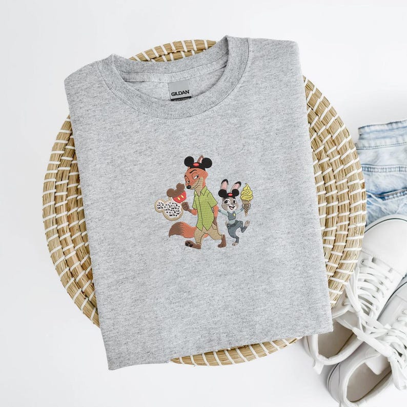 May include: A light gray crew neck sweatshirt featuring an embroidered design of two cartoon characters, a fox and a rabbit, holding ice cream cones. The sweatshirt is made of a soft material and is suitable for casual wear.