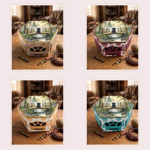 May include: A hexagonal box featuring a printed scene of a black dog sitting on a bridge over a pond. The sides of the box are decorated with paw print cutouts and patterns in various colors, including cream, maroon, yellow, and teal.