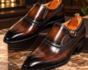 Puede incluir: Un par de zapatos de cuero marrón oscuro con hebilla y acabado bruñido, con punta afilada, detalles decorativos de brogue en el empeine y un cierre de hebilla de metal plateado en el lateral, cada uno con una horma de madera.