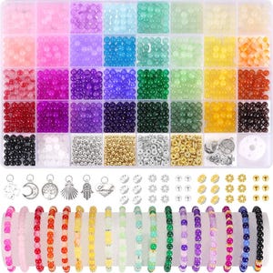 May include: A clear plastic storage container filled with assorted colorful round beads in various shades, including pink, purple, blue, green, yellow, and orange. The set includes metallic spacers, silver-toned charms, and several finished beaded bracelets.