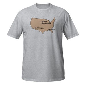 Puede incluir: Una camiseta gris jaspeado de manga corta con un mapa de los Estados Unidos en color tostado. El mapa incluye puntos negros y etiquetas de texto para las ubicaciones North Haverbrook, Ogdenville y Brockway en una fuente de estilo manual.