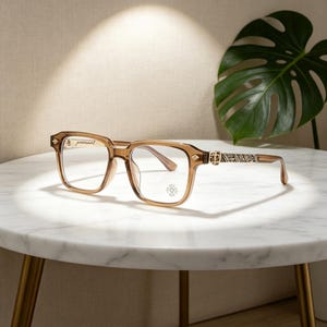 Peut inclure: Lunettes marron à monture carrée avec des branches décoratives et un logo subtil sur le verre. Les lunettes sont posées sur une table en marbre blanc avec des pieds dorés, avec une grande feuille verte en arrière-plan. Les montures sont de couleur marron clair.