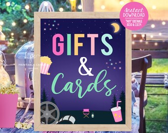 May include: A framed sign with the words "GIFTS & Cards" in colourful text against a dark blue night sky background. The sign includes illustrations of popcorn, a film reel, and a director's chair. The text "Instant Download" is also visible.