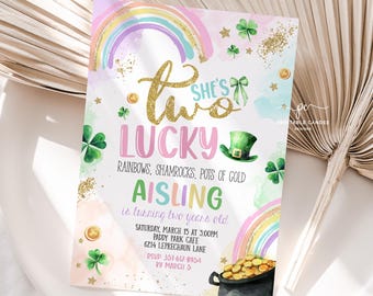 Pode incluir: Um convite com tema do Dia de São Patrício com um arco-íris, trevos e um pote de ouro. O texto diz "She's Two Lucky" e inclui detalhes para a festa de aniversário de dois anos de Aisling.