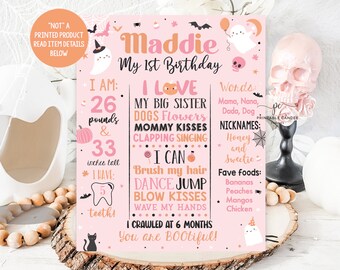 May include: A pink and orange birthday sign with Halloween-themed graphics. The sign includes the text "Maddie My 1st Birthday" and details about the child's age, weight (26 pounds), and height (33 inches).