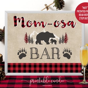 May include: Printable sign with a red and black buffalo plaid border. The sign says "Mom-osa Bar" with a black bear and cub illustration and paw prints.