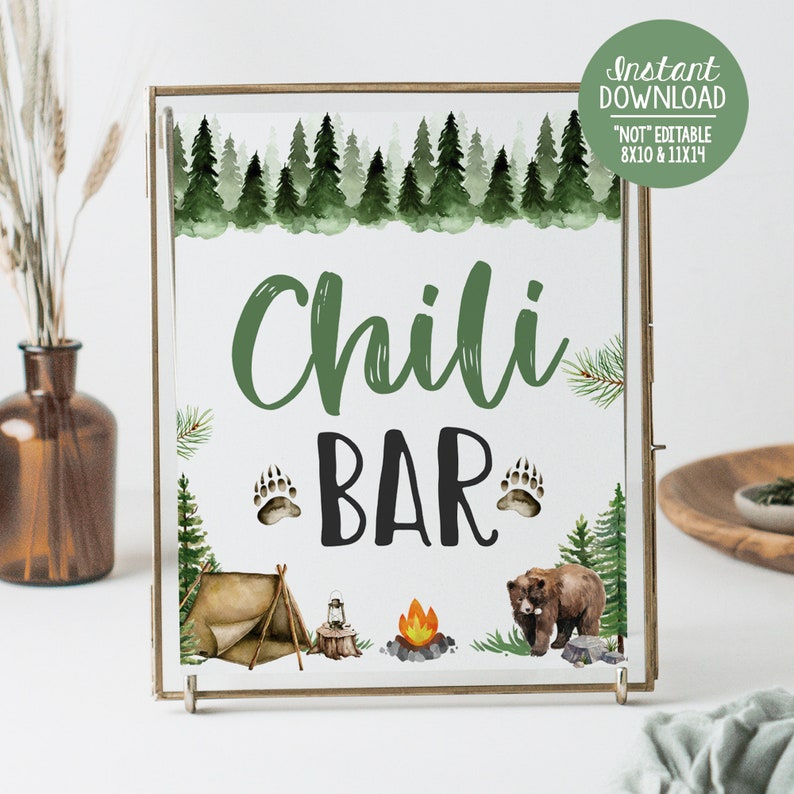 Op de afbeelding: Een printbaar bord met een rustiek bos-thema. Het bord zegt "Chili Bar" in groene en zwarte tekst. Het bord is versierd met een kampvuur, een tent, een lantaarn en berenpootafdrukken.