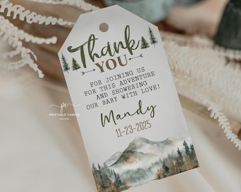 May include: A white thank you tag with a green and brown watercolor mountain scene. The text reads "Thank You for joining us for this adventure and showering our baby with love! Mandy 11-23-2025".