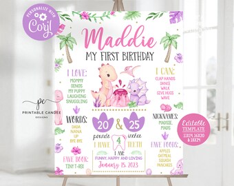May include: A pink and purple dinosaur-themed first birthday milestone poster with the name "Maddie" and details about her first year, including weight, height, words, and favorite foods. The poster is decorated with green palm trees, pink and purple flowers, and a pink and purple dinosaur.