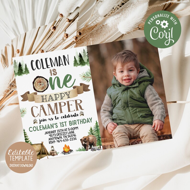 May include: A printable invitation for a first birthday party with a woodland camping theme. The invitation features a photo of a young boy, a bear, a campfire, and a tent. The text on the invitation reads "Coleman is One Happy Camper" and includes details about the party, such as the date, time, and location.