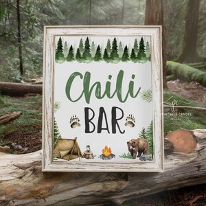 Op de afbeelding: Een printbaar bord met een rustieke houten lijst en een witte achtergrond. Het bord zegt "Chili Bar" in groene en zwarte tekst met poot afdrukken aan weerszijden van het woord "Bar". Het bord is versierd met een aquarel illustratie van een bos sc&egrave;ne met een tent, een kampvuur en een beer.