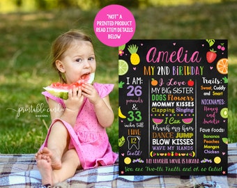 May include: A chalkboard style birthday sign with a tropical fruit theme. The sign says "Amelia My 2nd Birthday". It lists facts about the birthday girl, including her age, weight, height, favorite foods, and favorite movie. The sign is decorated with colorful fruit illustrations.