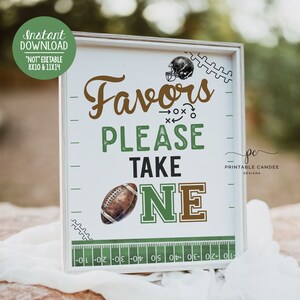 May include: A white sign with a green and brown football theme. The sign says "Favors Please Take One" with a football graphic. The sign is framed in a white frame and has a green and white football field design at the bottom.