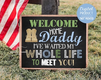May include: A chalkboard sign with the text "Welcome Home Daddy I've waited my whole life to meet you!" in green, blue, and yellow lettering. The sign also features a pair of brown military boots.