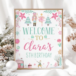 May include: A framed print with a gold border features a watercolor design with the text "WELCOME TO Clara's 5th BIRTHDAY". The design includes a nutcracker, ballerina, Christmas trees, and other festive elements in pink, teal, and gold.