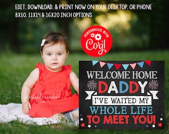 May include: A baby girl in a red dress sits on a white blanket in a grassy area. She is holding a chalkboard sign that says "Welcome Home Daddy I've waited my whole life to meet you!" The sign is decorated with red, white, and blue stars and fireworks.