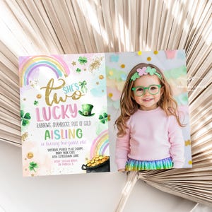 May include: A printable invitation for a girl's second birthday party with a St. Patrick's Day theme. The invitation features a rainbow, shamrocks, a pot of gold, and the text "She's Two Lucky". The invitation also includes a space for a photo of the birthday girl.