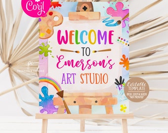 Può includere: Un cavalletto in legno espone un cartello colorato con la scritta "WELCOME TO Emerson's ART STUDIO". Il cartello presenta schizzi di vernice, un arcobaleno e una tavolozza. È un modello modificabile, disponibile in formati di 20x25, 28x35 e 40x50 cm.