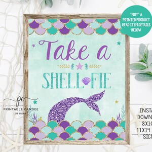 Puede incluir: Señal imprimible con una cola de sirena y conchas marinas, con el texto "Take a Shell-fie" en morado y turquesa. La señal está enmarcada en madera y tiene un fondo blanco.