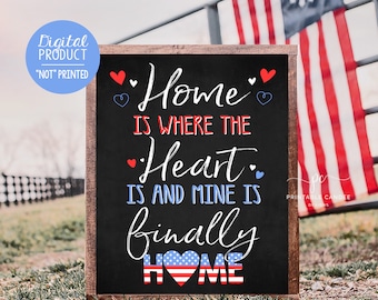 May include: A black chalkboard sign with white text that reads "Home is where the heart is and mine is finally home". The sign is decorated with red and blue hearts and a red, white, and blue heart with stars in the center. The sign is in front of a wooden fence and a red, white, and blue American flag.