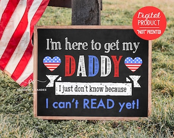 May include: A chalkboard sign with the text "I'm here to get my DADDY. I just don't know because I can't READ yet!" The sign is decorated with two red, white, and blue hearts.