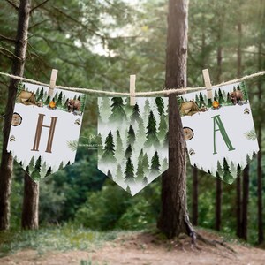 Op de afbeelding: Een banner met een bos-thema met de letters "H" en "A" in een bruin en groen lettertype. De banner is versierd met een aquarelpatroon van groene bomen, een kampvuur, een tent en een beer.