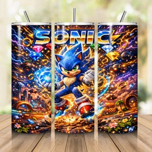 May include: A cylindrical tumbler featuring a vibrant graphic of the character Sonic the Hedgehog surrounded by golden rings, colorful gemstones, and lightning effects against a dark, energetic background with the word SONIC at the top.