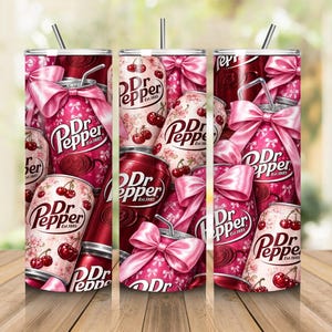 May include: A cylindrical tumbler featuring a repeating pattern of Dr Pepper soda cans in shades of pink and red. The design includes illustrations of cherries, pink bows, and white ribbon motifs. A thin metal straw is inserted into the top lid.