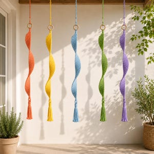 May include: Six colorful macrame hanging decorations in orange, yellow, blue, green, and purple. Each has a wooden ring at the top and a tassel at the bottom. The spiral design adds a decorative touch to any space.