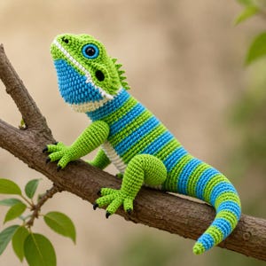 May include: A handmade crochet lizard in shades of green and blue, perched on a brown branch. The lizard features a detailed design with stripes and a textured appearance. The reptile's eyes are black and blue, and its claws are black.