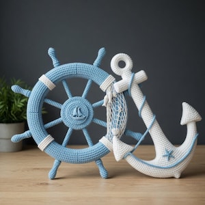 May include: A handcrafted crochet ship's wheel in light blue and white, featuring a central sailboat emblem and a white fishing net accent. Beside it stands a white crochet anchor with light blue trim and a small blue starfish detail.