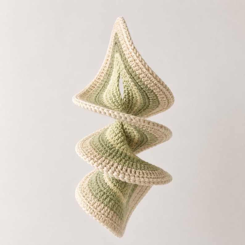 May include: A spiraling, handmade crochet mobile in shades of green and cream. The mobile features a repeating geometric pattern, with each section gradually changing color. The crochet work is detailed, and the overall design is modern and artistic.
