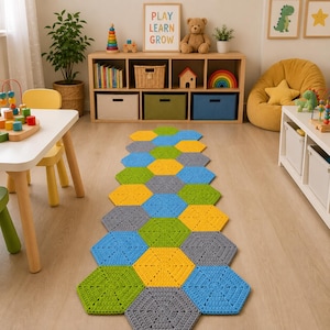 May include: A handmade crochet rug with a hexagonal design. The rug is made up of yellow, blue, green, and grey hexagons. The rug is placed on a light wooden floor in a child's playroom. The room also has a wooden shelf and a yellow beanbag.