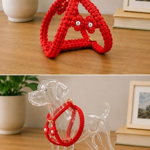 May include: A vibrant red macrame dog harness with gold-colored hardware and pearl accents. The harness is displayed on a wooden surface, and a clear glass dog figurine is wearing the harness. The design includes floral details.