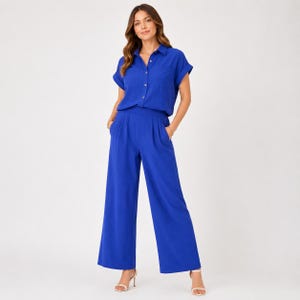 May include: A vibrant royal blue two-piece set consisting of a short-sleeved button-down shirt with a collar and a chest pocket, paired with matching high-waisted wide-leg trousers that feature side pockets and a clean, tailored silhouette.