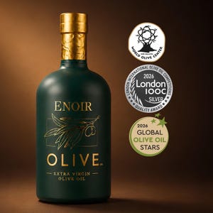 May include: A dark green glass bottle of Enoir Olive Co. extra virgin olive oil with a gold cap. The label features gold text and an olive branch illustration. Three circular award seals are displayed, including London IOOC 2026 Silver and Global Olive Oil Stars 2026.