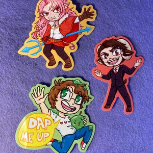 May include: Three cartoon stickers on a purple background. One features a character with pink hair, a red cape, and a trident. Another shows a character in a suit with ram horns. The third sticker has a character with glasses and the text "DAP ME UP".